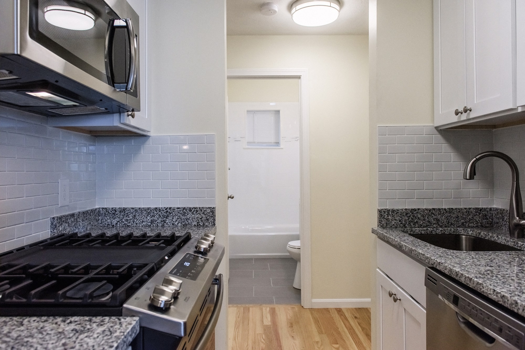 the view of a kitchen with a stove and a sink and a bathroom